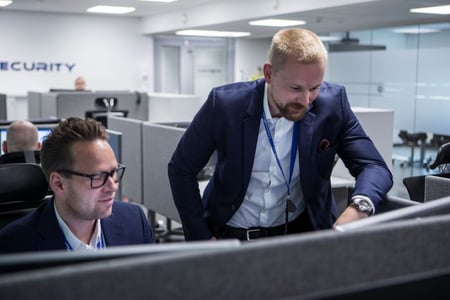 To ansatte i Netsecurity ser på en PC i et åpent kontorlandskap
