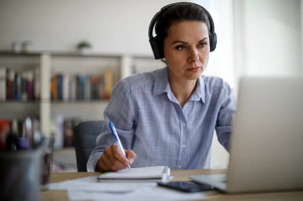 Kvinne som ser på laptop og noterer